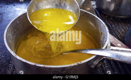Verser le jaune, fondu, du beurre clarifié, jusque dans la casserol, lors d'une cuisine de restaurant Banque D'Images
