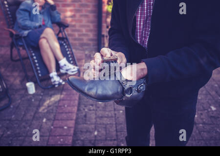 Le polissage est un homme souliers dehors dans un jardin Banque D'Images