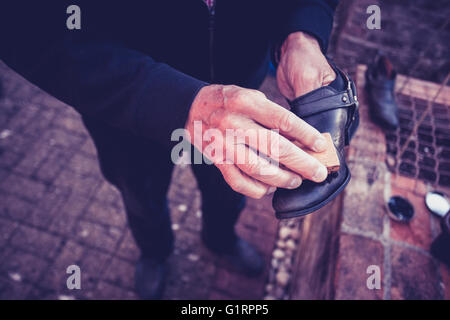 Le polissage est un homme souliers dehors dans un jardin Banque D'Images