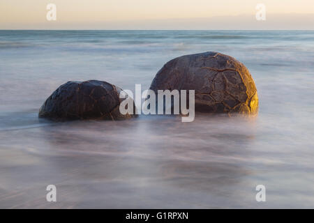 Moeraki Boulders sur l'Koekohe plage, la Nouvelle-Zélande durant le lever du soleil (longue exposition) Banque D'Images