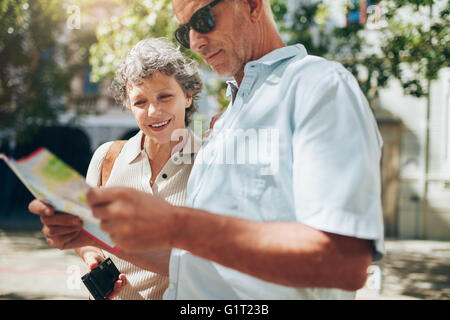 Close up shot of senior en vacances la lecture d'un plan de la ville. L'homme et la femme mature à l'aide de plan de ville pour les directions de la ville. Banque D'Images