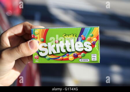 Close up of hand holding fort de bonbons Skittles sour dans emballage vert Banque D'Images