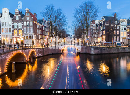 Une vue sur les ponts de l'Leidsegracht et Keizersgracht intersection à Amsterdam au crépuscule. Le sentier d'un bateau peut Banque D'Images