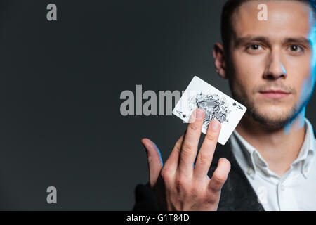 Portrait du jeune magicien holding as sur fond gris Banque D'Images