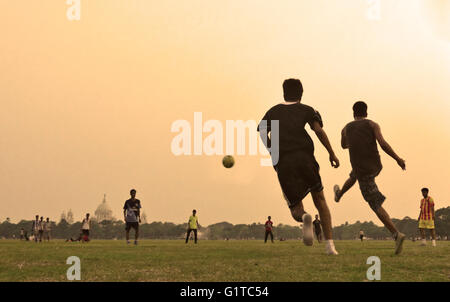 Jouer au football dans la région de Maidan avec Victoria Memorial à l'arrière-plan, Kolkata, West Bengal, India Banque D'Images