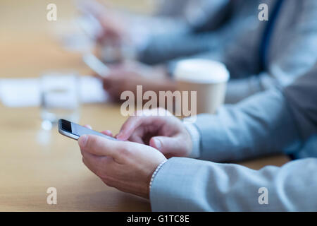 Close up of businessman using cell phone in meeting Banque D'Images