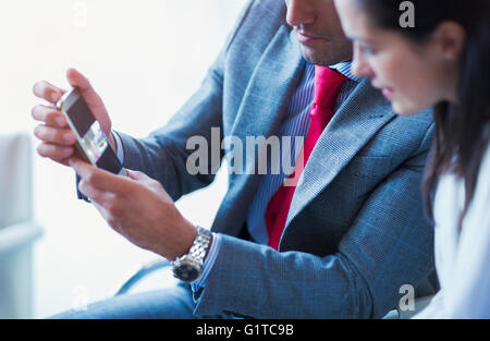 Businessman showing cell phone vidéo pour businesswoman Banque D'Images