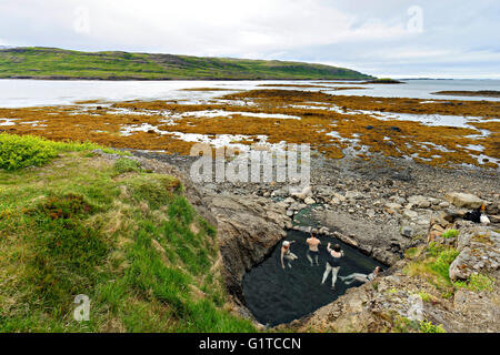 Groupe de personnes se baignant dans une source thermale naturelle ( Hellulaug Vatnsfjšrdur), fjord, Westfjords, l'Islande, l'Europe. Banque D'Images