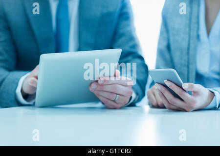 Businessman and businesswoman using digital tablet and cell phone Banque D'Images