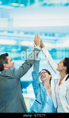 Les gens d'affaires enthousiastes with arms raised in office Banque D'Images