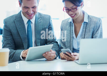 Businessman and businesswoman using digital tablet and cell phone in office Banque D'Images