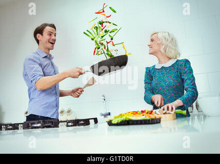 Surpris couple cooking renversant les légumes dans la poêle dans la cuisine Banque D'Images