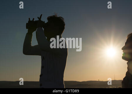 Les réfugiés kurdes regarder les raids aériens des alliés, comme le soleil se couche, à la ville syrienne de Kobani, à partir d'une colline qui surplombe la ville, près de la ville turque de Suruc, à la frontière turco-syrienne. Des milliers de Kurdes ont été forcés d'abandonner la ville syrienne de Kobani, qui est assiégée par les forces de l'État islamique. La plupart d'entre eux vivent dans des camps de réfugiés dans la ville turque de Suruc. Banque D'Images