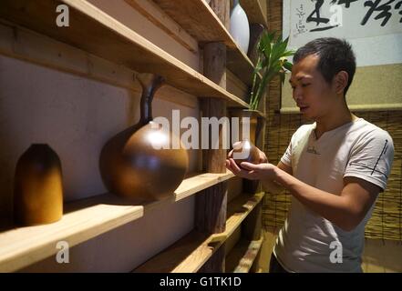 (160519) -- BEIJING, 19 mai 2016 (Xinhua) -- Xie Zhenhua regarde ses travaux en porcelaine de Chine orientale, comté de Nanfeng, province de Jiangxi, le 18 mai 2016. Xie Zhenhua, un 1988-né gradutate d'instituts en céramique de Jingdezhen, est maintenant propriétaire d'un atelier de céramique, qui sont principalement engagés dans l'élaboration de Baishe culture et four four Baishe produits céramiques. Baishe four qui était autrefois l'une des cinq célèbres de fours à céramique de la province durant la dynastie Song (960-1279), qui n'a de nombreux grands fours de Jingdezhen, bien connu en tant que capitale de la porcelaine de Chine. Le four de Baishe, cependant, sont enfin entrés en Banque D'Images