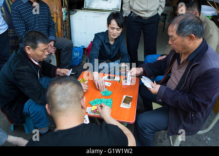 Groupe d'hommes jouant aux cartes chinois autour d'une table d'orange sur le trottoir, scène de rue à Nanjing, Chine Banque D'Images