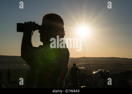 Les réfugiés kurdes regarder les raids aériens des alliés, comme le soleil se couche, à la ville syrienne de Kobani, à partir d'une colline qui surplombe la ville, près de la ville turque de Suruc, à la frontière turco-syrienne. Des milliers de Kurdes ont été forcés d'abandonner la ville syrienne de Kobani, qui est assiégée par les forces de l'État islamique. La plupart d'entre eux vivent dans des camps de réfugiés dans la ville turque de Suruc. Banque D'Images