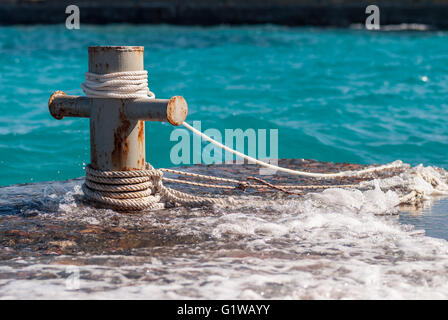 Amarrage bateau rouillé bollard avec cordes et claire de la mer turquouse ocen sur l'eau contexte Banque D'Images