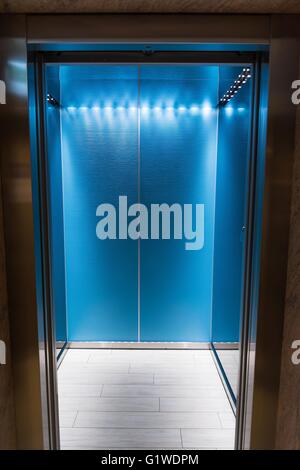 Un ascenseur moderne bleu vide ou ascenseur avec portes métalliques qui sont ouverts dans le bâtiment avec l'éclairage. Photo verticale Banque D'Images