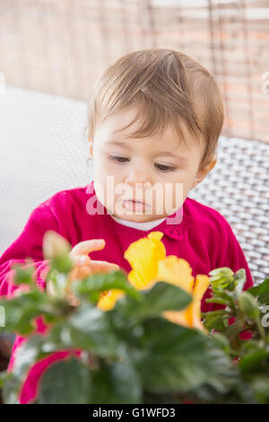 Curieux d'un an bébé girl fleurs jaune Banque D'Images