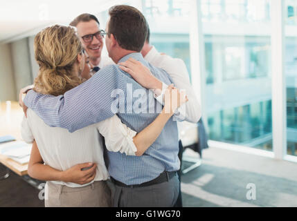 Smiling business people hugging in trainent dans la salle de conférence Banque D'Images