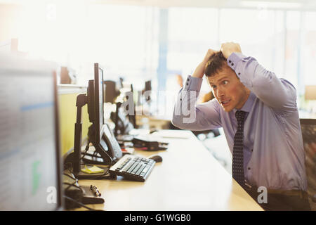 Souligné businessman pulling his cheveux at computer in office Banque D'Images