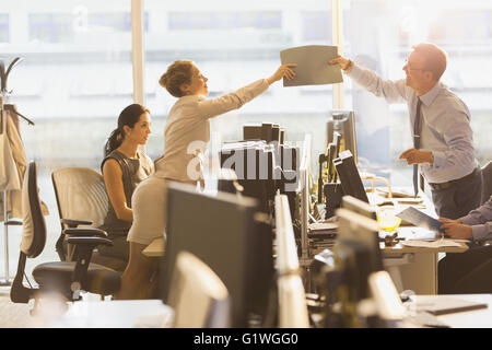 Businessman and businesswoman passant dossier sur ordinateurs de bureau Banque D'Images