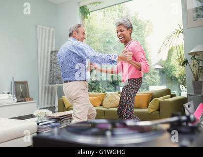 Maturité ludique couple dancing in living room Banque D'Images