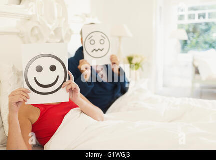 Portrait de couples holding smiling face et fronçant les impressions face au lit Banque D'Images