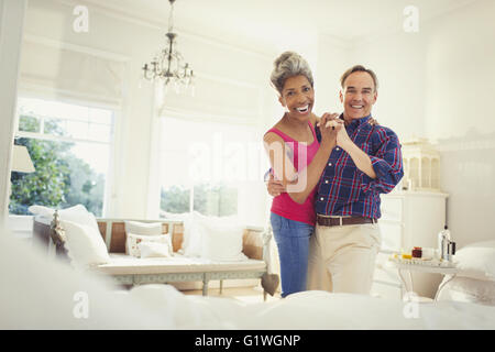 Portrait of smiling young couple dancing in bedroom Banque D'Images