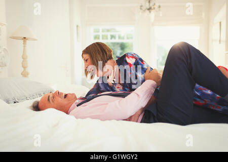 Bien-habillé mature couple laughing on bed Banque D'Images