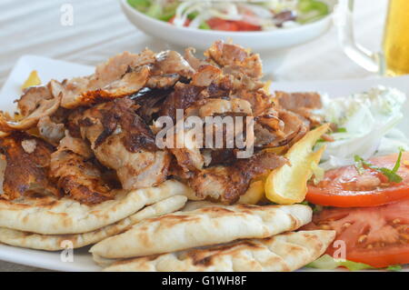 Les gyros de porc sur une assiette avec de la salade et un verre de porter Banque D'Images