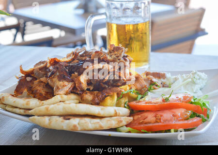 Les gyros de porc sur une assiette avec de la salade et un verre de porter Banque D'Images