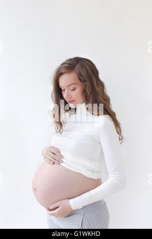 Femme enceinte en caressant son ventre over white Banque D'Images