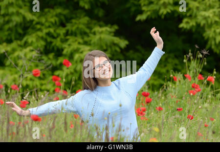 Jeune fille jouant dans un champ de coquelicots Banque D'Images