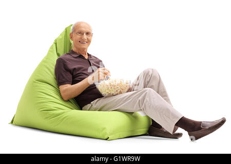 Man eating popcorn assis sur un pouf vert et regardant la caméra isolé sur fond blanc Banque D'Images