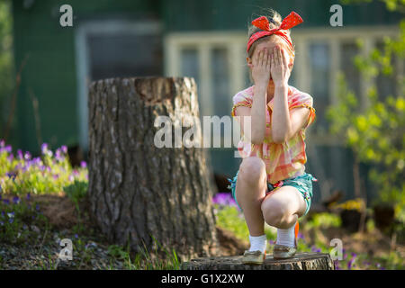 Cute little girl couvrant ses yeux avec ses mains. Ne rien voir, rien entendre, de ne rien dire à personne - une série de trois photos. Banque D'Images