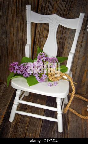 Bouquet de lilas avec corde noeud celtique coeur sur chaise en bois blanc. Banque D'Images