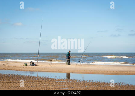 Un pêcheur et l'homme avec deux cannes à pêche sur la plage de la mer du Nord au cours de la pêche en mer la concurrence à Egmond-aan-Zee Pays-Bas Banque D'Images