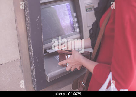 Une jeune femme se retire de l'argent dans un distributeur Banque D'Images