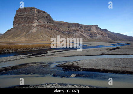 L'écoulement glaciaire se retrouvent dans la plaine de sable volcanique Skeidararsandur, derrière le massif de roche ou Lómagnúpurur Lomagnupur Banque D'Images