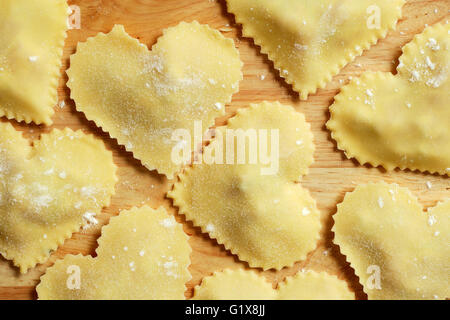 Photo de pâtes maison en forme de cœur assis sur un comptoir en bois. Banque D'Images