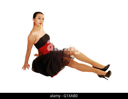 Un beau et grand jeune femme asiatique dans une robe noire et ceinture rouge assis sur sur le sol pour l'arrière-plan blanc. Banque D'Images