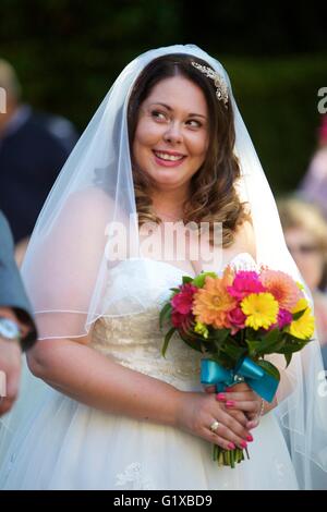 Bride smiling holding fleurs pendant le jour de son mariage robe de mariage porter Banque D'Images