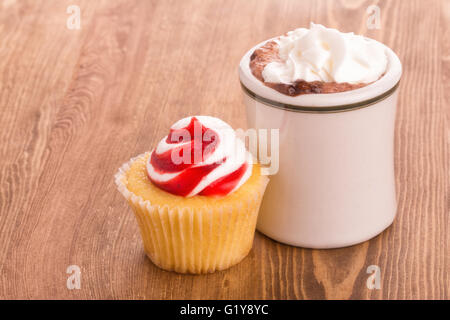 Cupcake fraise avec une tasse de chocolat chaud sur la table en bois - avec un léger fléchissement filtre pour un effet nostalgique Banque D'Images