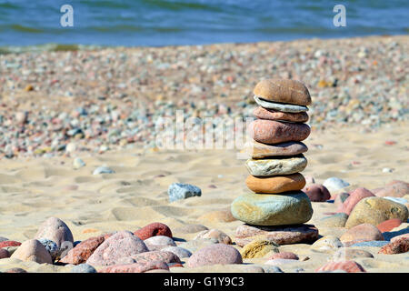 Pyramide de cailloux de couleur sur une plage ensoleillée Banque D'Images