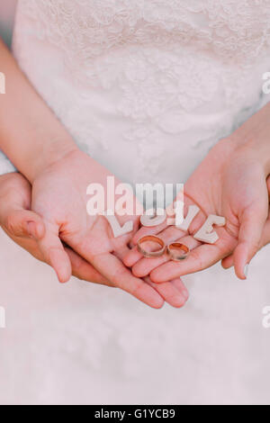 Anneaux de mariage d'or, lettres en bois sur les paumes de la jeune mariée et se toilettent, close-up Banque D'Images