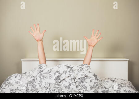 Une femme est forme de sous les couvertures dans un lit Banque D'Images