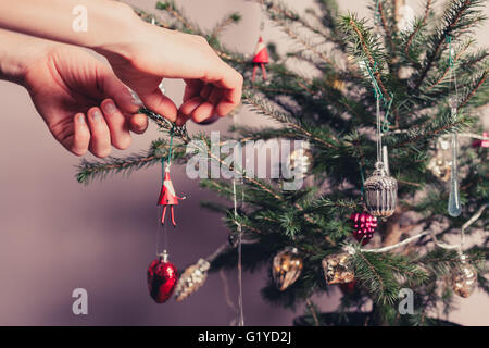 Mains décorer un arbre de Noël avec toutes sortes de choses colorées Banque D'Images