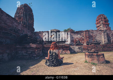 Une jeune femme est assise et de méditer parmi les ruines d'un ancien temple bouddhiste Banque D'Images