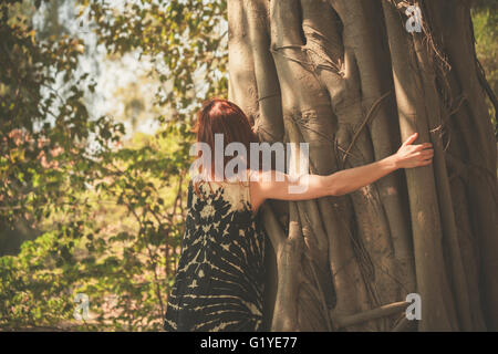 Une jeune femme s'embrasser et s'étreindre un arbre géant Banque D'Images